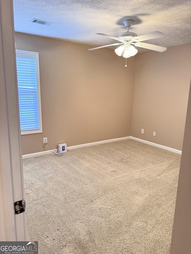 spare room featuring a ceiling fan, a textured ceiling, carpet, and baseboards