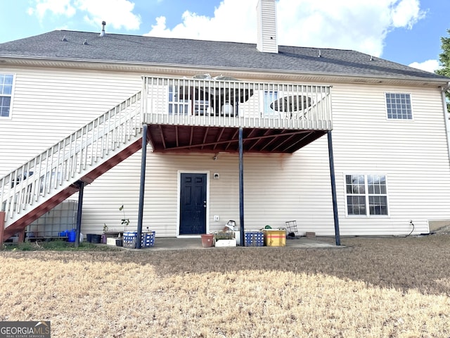 rear view of property featuring stairs, a chimney, and a deck