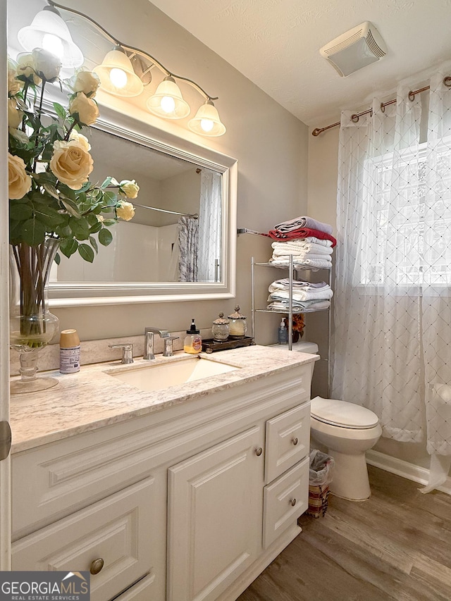 2985 Catalina Dr, Decatur, GA 30032 - full bathroom with a shower with shower curtain, toilet, vanity, wood finished floors, and visible vents