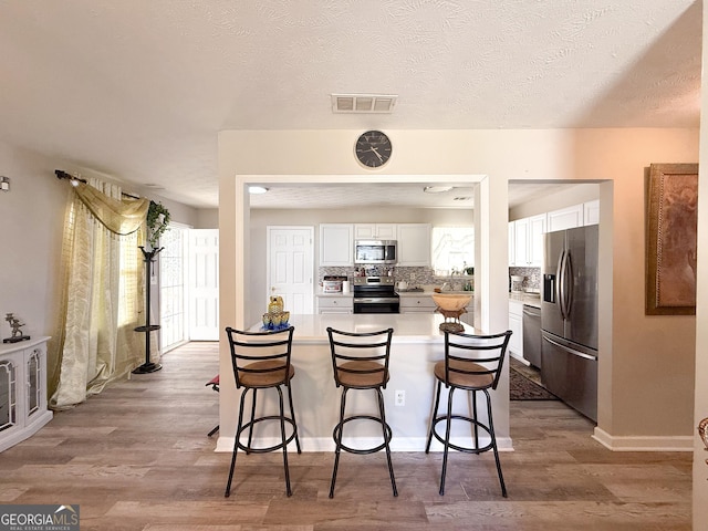 2985 Catalina Dr, Decatur, GA 30032 - kitchen with visible vents, white cabinets, a breakfast bar area, and stainless steel appliances