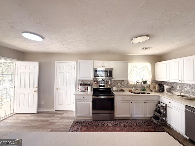 2985 Catalina Dr, Decatur, GA 30032 - kitchen with light countertops, a sink, stainless steel appliances, visible vents, and white cabinets