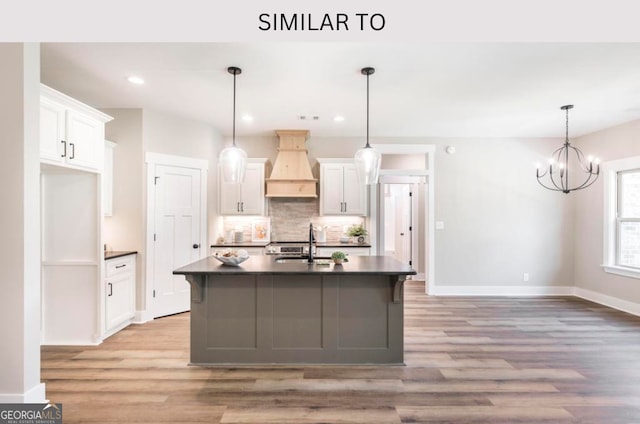 107 Tilden Way, Perry, GA 31069 - kitchen featuring premium range hood, dark countertops, light wood-type flooring, tasteful backsplash, and white cabinets