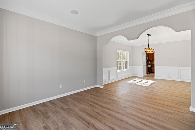 82 Bantry Park Dr, Newnan, GA 30263 - spare room with a chandelier, light wood finished floors, arched walkways, crown molding, and wainscoting
