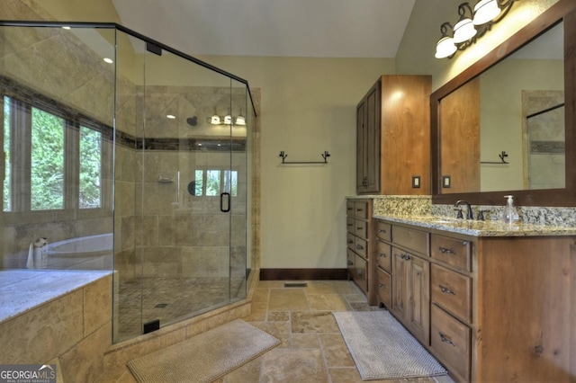bathroom with a stall shower, baseboards, vanity, and stone tile flooring