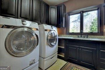 clothes washing area with washing machine and clothes dryer, cabinet space, and a sink