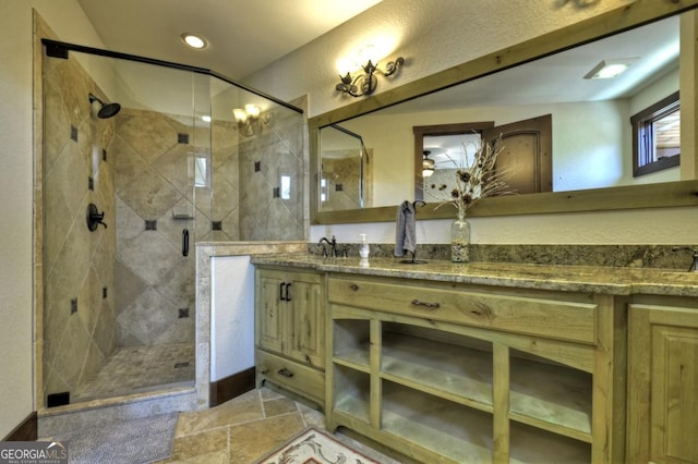 full bathroom featuring a stall shower, stone tile floors, a sink, double vanity, and recessed lighting