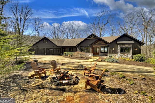 view of front facade featuring stone siding, a garage, and an outdoor fire pit