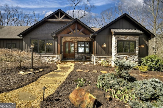 view of front facade with french doors, board and batten siding, and stone siding