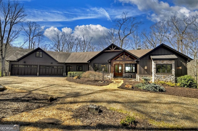 view of front of property with stone siding, board and batten siding, driveway, and a garage