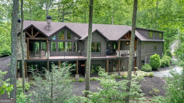 rear view of property featuring board and batten siding, roof with shingles, and a chimney
