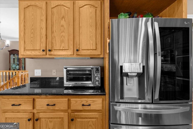 kitchen featuring stainless steel refrigerator with ice dispenser, dark stone countertops, and a toaster