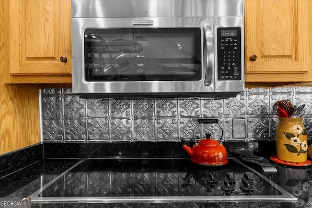 details featuring decorative backsplash and stainless steel microwave