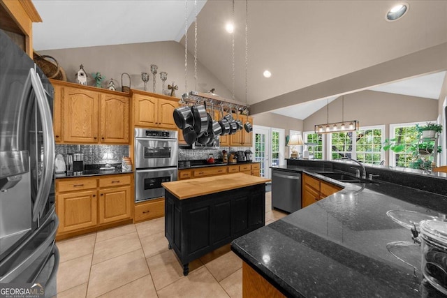 kitchen featuring tasteful backsplash, a sink, appliances with stainless steel finishes, light tile patterned floors, and hanging light fixtures