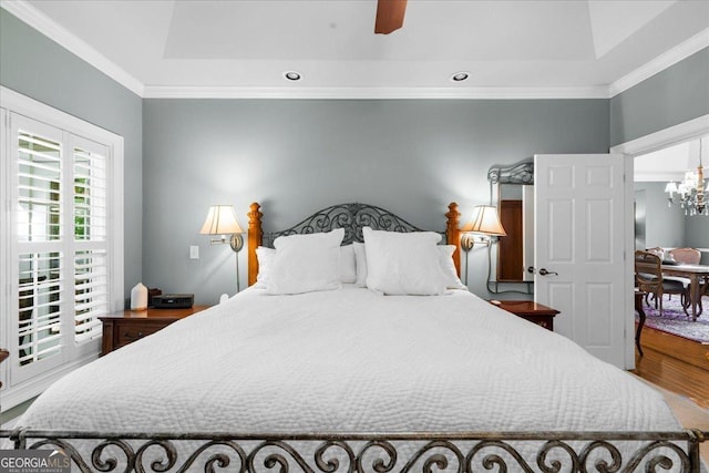 bedroom with a raised ceiling, ornamental molding, recessed lighting, and wood finished floors