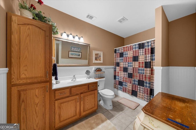 full bathroom featuring toilet, visible vents, and a wainscoted wall
