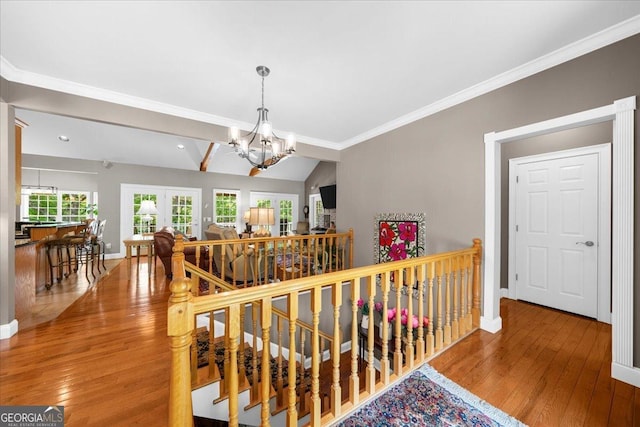 corridor featuring an inviting chandelier, baseboards, hardwood / wood-style flooring, and an upstairs landing