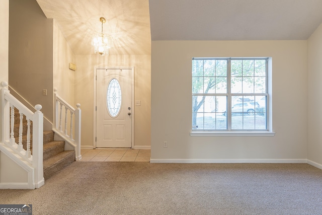 foyer with a chandelier, light tile patterned floors, plenty of natural light, and light colored carpet