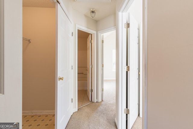 corridor with baseboards and light carpet