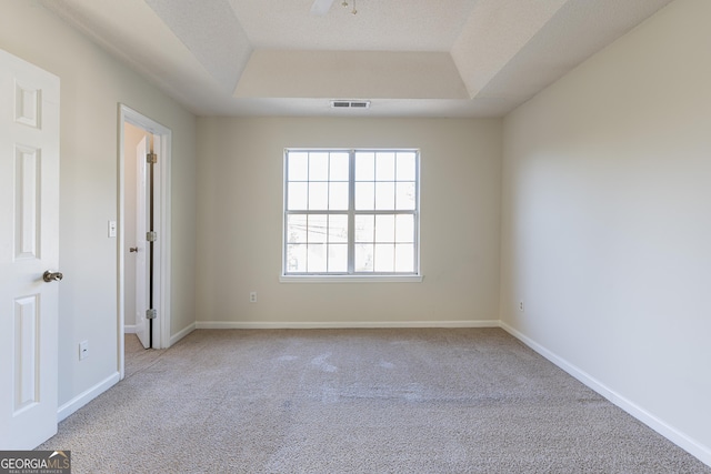 spare room featuring visible vents, baseboards, a ceiling fan, carpet floors, and a tray ceiling