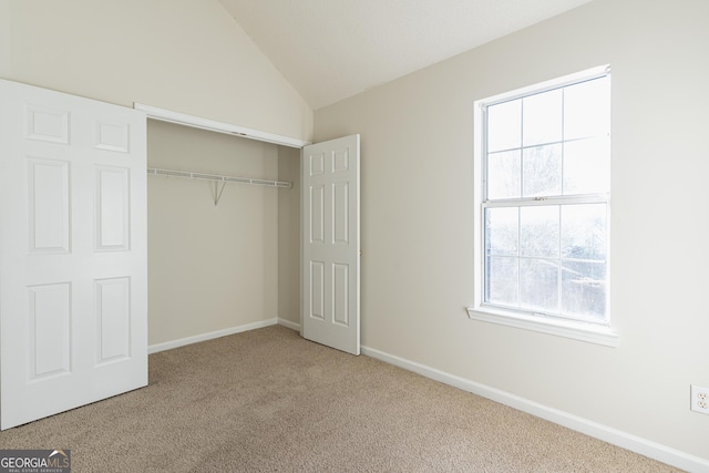unfurnished bedroom featuring carpet floors, baseboards, a closet, and vaulted ceiling