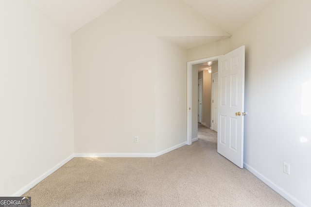 unfurnished room featuring carpet floors, baseboards, and vaulted ceiling