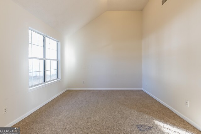 spare room featuring baseboards, vaulted ceiling, visible vents, and carpet flooring