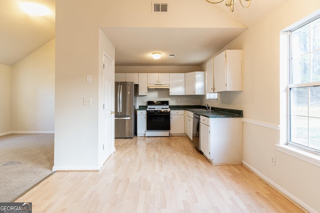 kitchen featuring under cabinet range hood, range with gas cooktop, dishwasher, visible vents, and freestanding refrigerator
