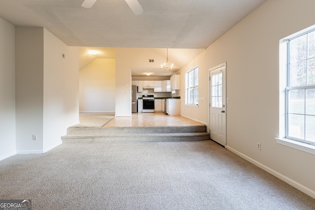 unfurnished living room featuring a healthy amount of sunlight, lofted ceiling, and light colored carpet