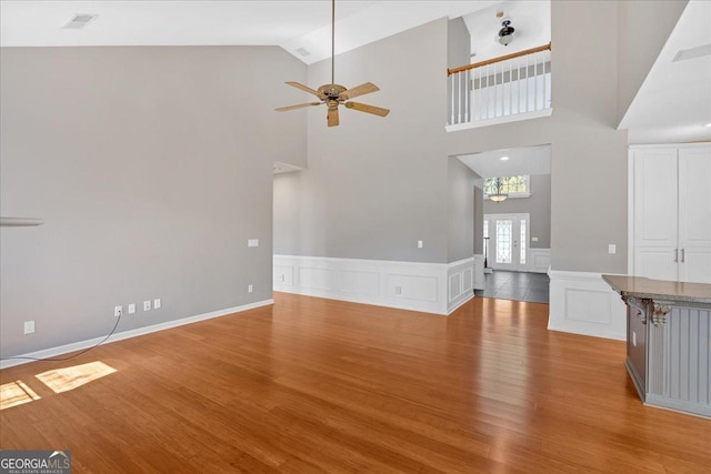 2445 Ridgelake Dr, Villa Rica, GA 30180 - unfurnished living room featuring wood finished floors, ceiling fan, a wainscoted wall, high vaulted ceiling, and a chandelier
