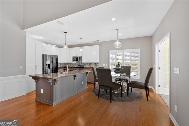 2445 Ridgelake Dr, Villa Rica, GA 30180 - kitchen with stainless steel appliances, white cabinets, light wood-style flooring, tasteful backsplash, and recessed lighting