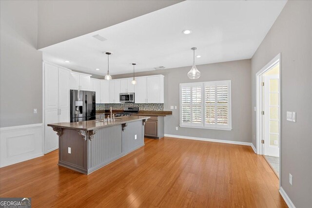 2445 Ridgelake Dr, Villa Rica, GA 30180 - kitchen featuring appliances with stainless steel finishes, light wood-type flooring, white cabinetry, a breakfast bar area, and recessed lighting