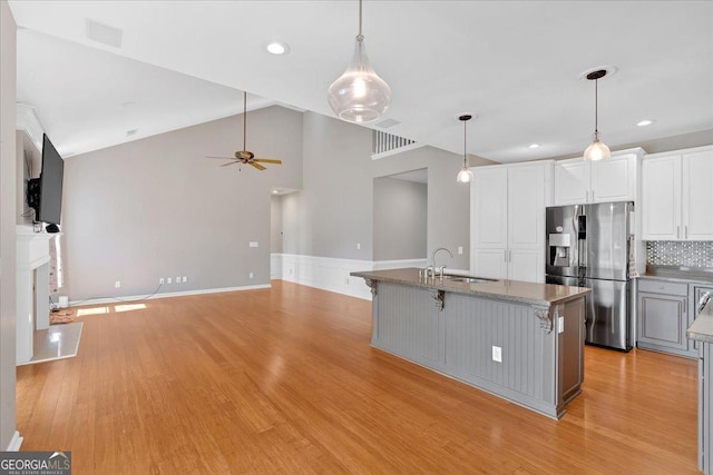 2445 Ridgelake Dr, Villa Rica, GA 30180 - kitchen with stainless steel fridge, light wood-style floors, white cabinetry, ceiling fan, and decorative backsplash