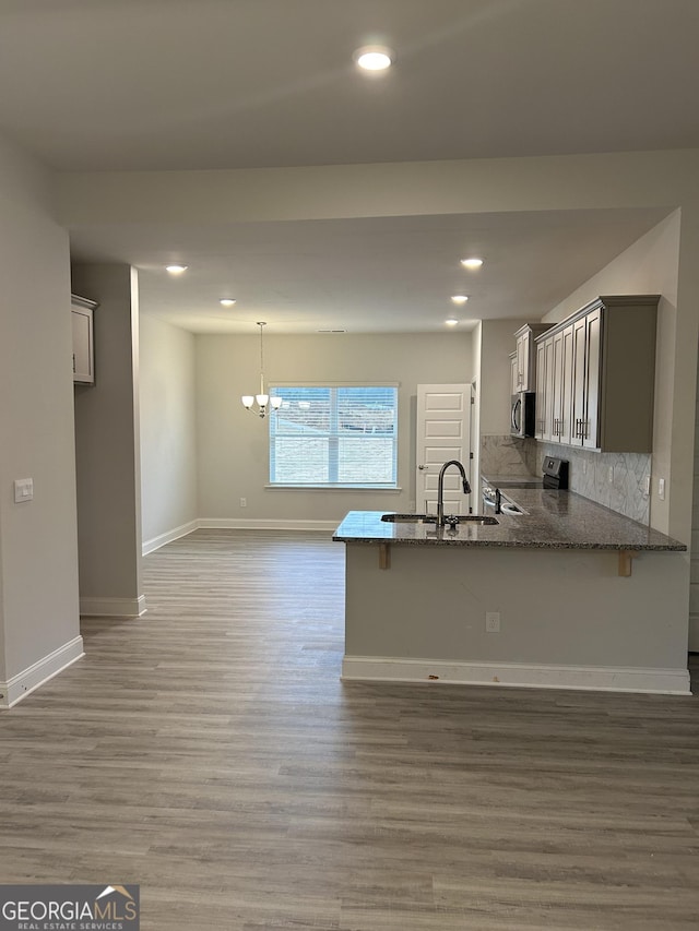 kitchen featuring a sink, dark stone countertops, a ceiling fan, and wood finished floors
