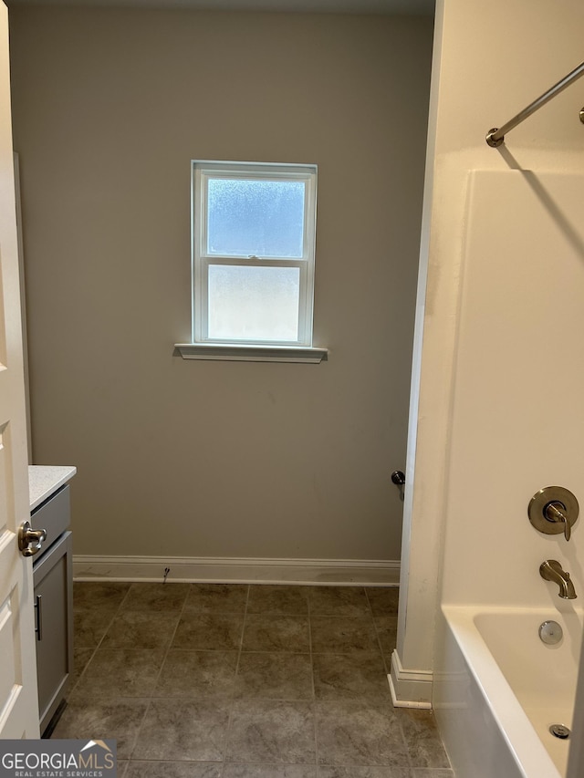bathroom featuring vanity, baseboards, and tub / shower combination