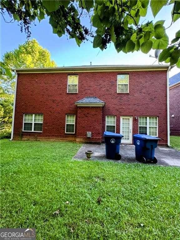 rear view of house featuring brick siding and a yard