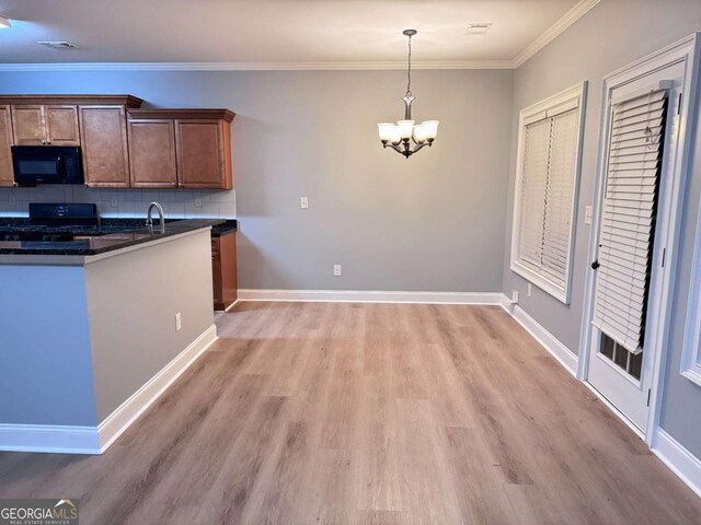 kitchen featuring a chandelier, dark countertops, tasteful backsplash, light wood-type flooring, and black appliances