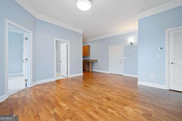unfurnished living room with baseboards, crown molding, and wood finished floors
