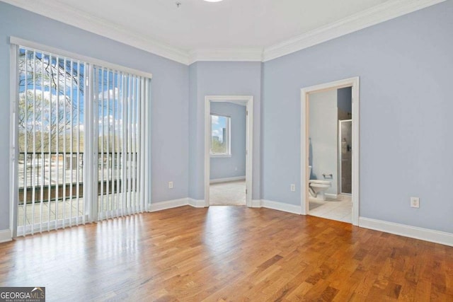 empty room with baseboards, crown molding, and wood finished floors