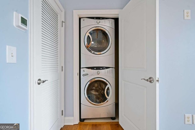 washroom with light wood-style flooring, stacked washer and dryer, and laundry area