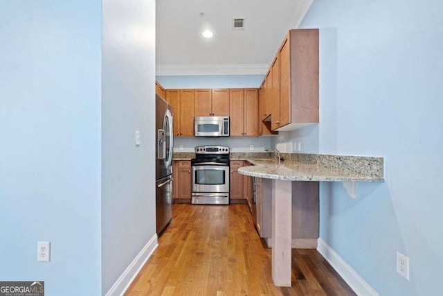 kitchen with baseboards, light stone countertops, stainless steel appliances, and light wood-type flooring