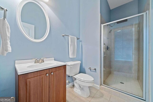 bathroom with a stall shower, toilet, vanity, tile patterned flooring, and baseboards