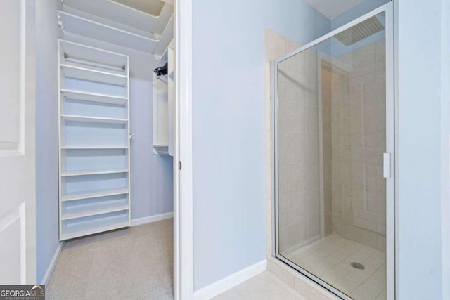 full bath featuring a stall shower, baseboards, and a spacious closet