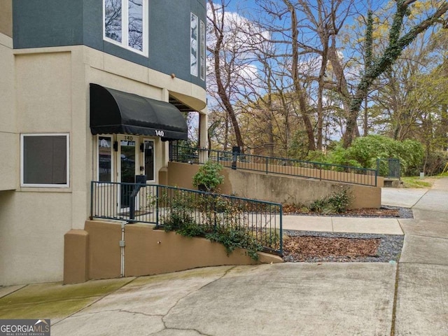 entrance to property featuring stucco siding and fence