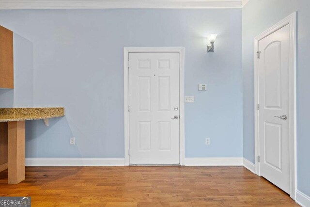 unfurnished dining area featuring ornamental molding, baseboards, and wood finished floors