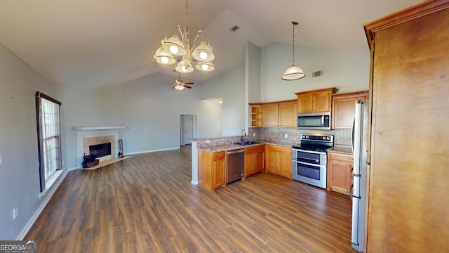 kitchen featuring a peninsula, open floor plan, a sink, dark wood finished floors, and appliances with stainless steel finishes