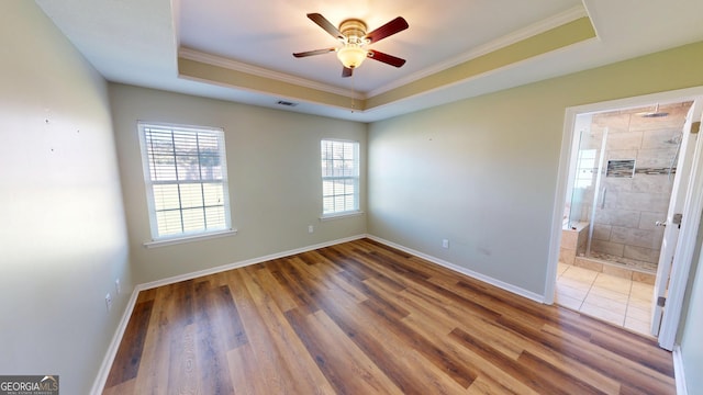 spare room with ornamental molding, a raised ceiling, ceiling fan, and wood finished floors