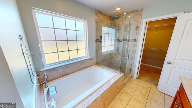 full bath with a garden tub, tile patterned flooring, a spacious closet, and a shower stall