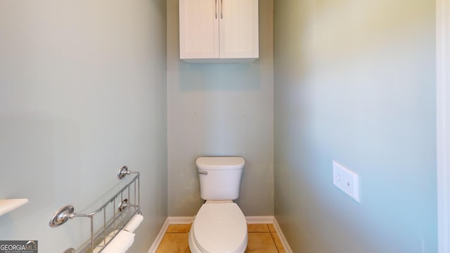 half bath featuring baseboards, tile patterned floors, and toilet