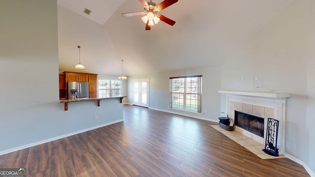 unfurnished living room with visible vents, wood finished floors, a fireplace, ceiling fan, and high vaulted ceiling