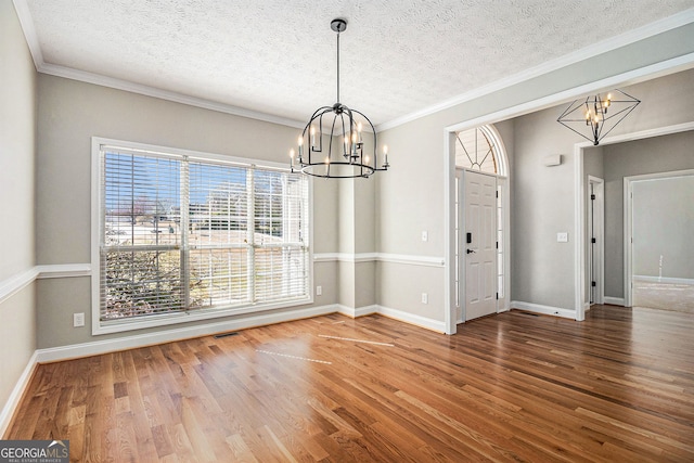 1092 Shumard Ln, Mcdonough, GA 30252 - unfurnished dining area with a chandelier, wood finished floors, a textured ceiling, and ornamental molding
